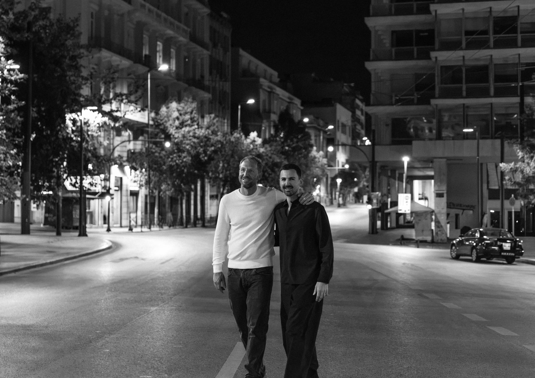 Jack and Lefteris walking arm in arm down an empty Athens street at night
